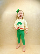 girl smiling while wearing shamrock sweater and leggings