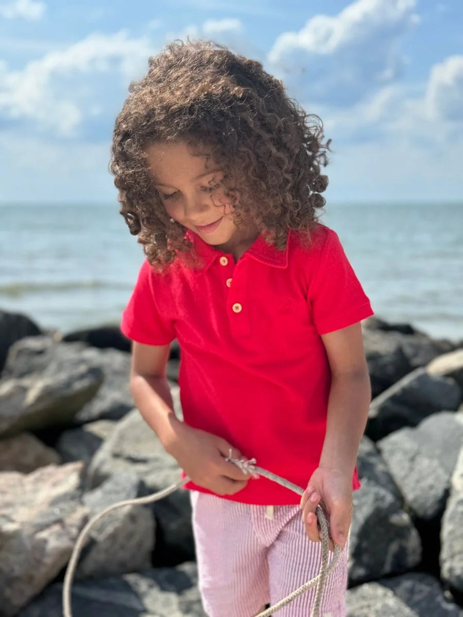 boy wearing red polo shirt at the beach