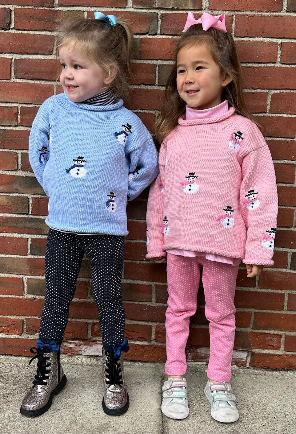 two girls wearing blue and pink snowmen sweaters