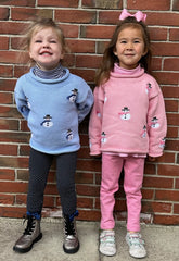 two girls wearing blue and pink snowmen sweaters