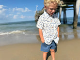 boy wearing sailboat shirt on the beach