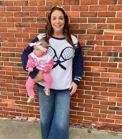 women wearing tennis sweater holding baby also wearing tennis sweater in pink