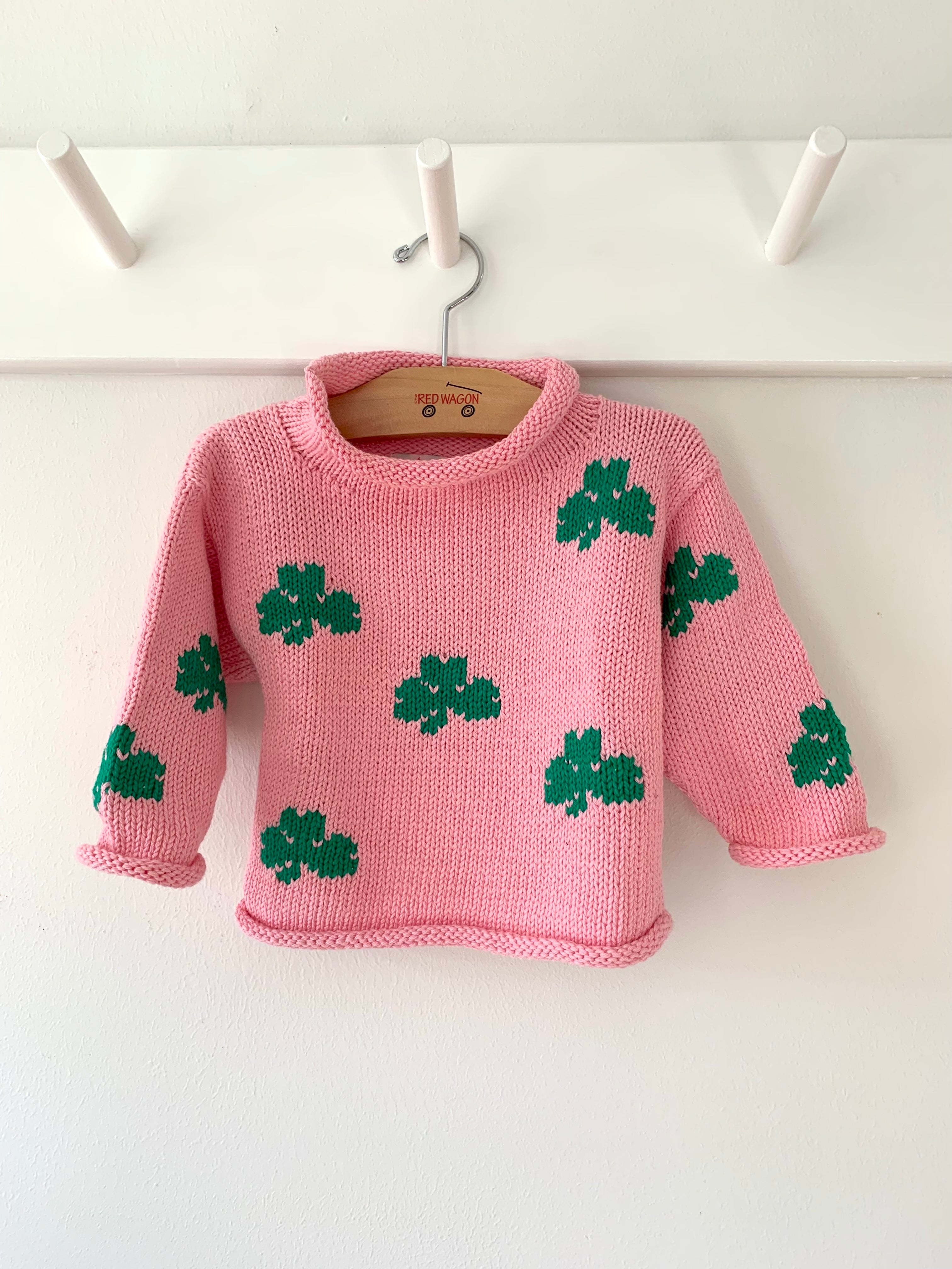 pink shamrock sweater hanging on a peg