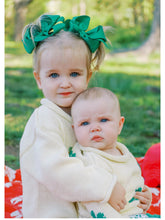 big sister and little sister wearing sweaters and green hair bows